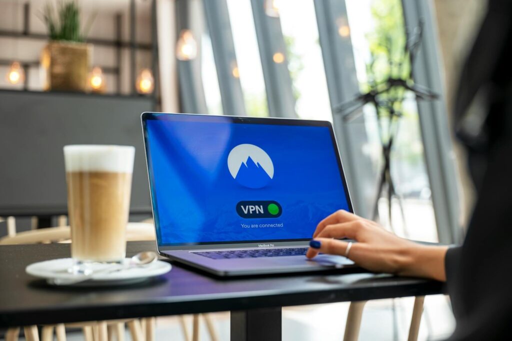 White Label Cybersecurity Services for MSPs 1 A person using a laptop with a VPN connection in a modern cafe setting, showcasing remote work and internet security.